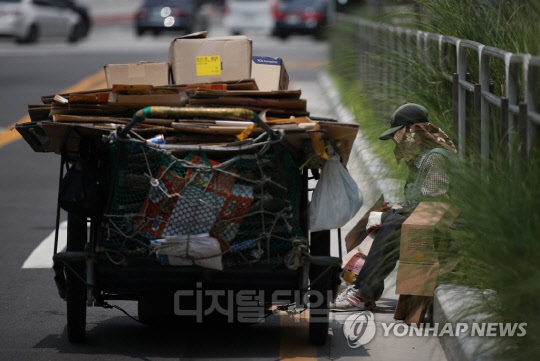 서울 마포구 도로에서 모자 아래 손수건을 덧쓴 한 어르신이 폐지를 정리하고 있다. 연합뉴스